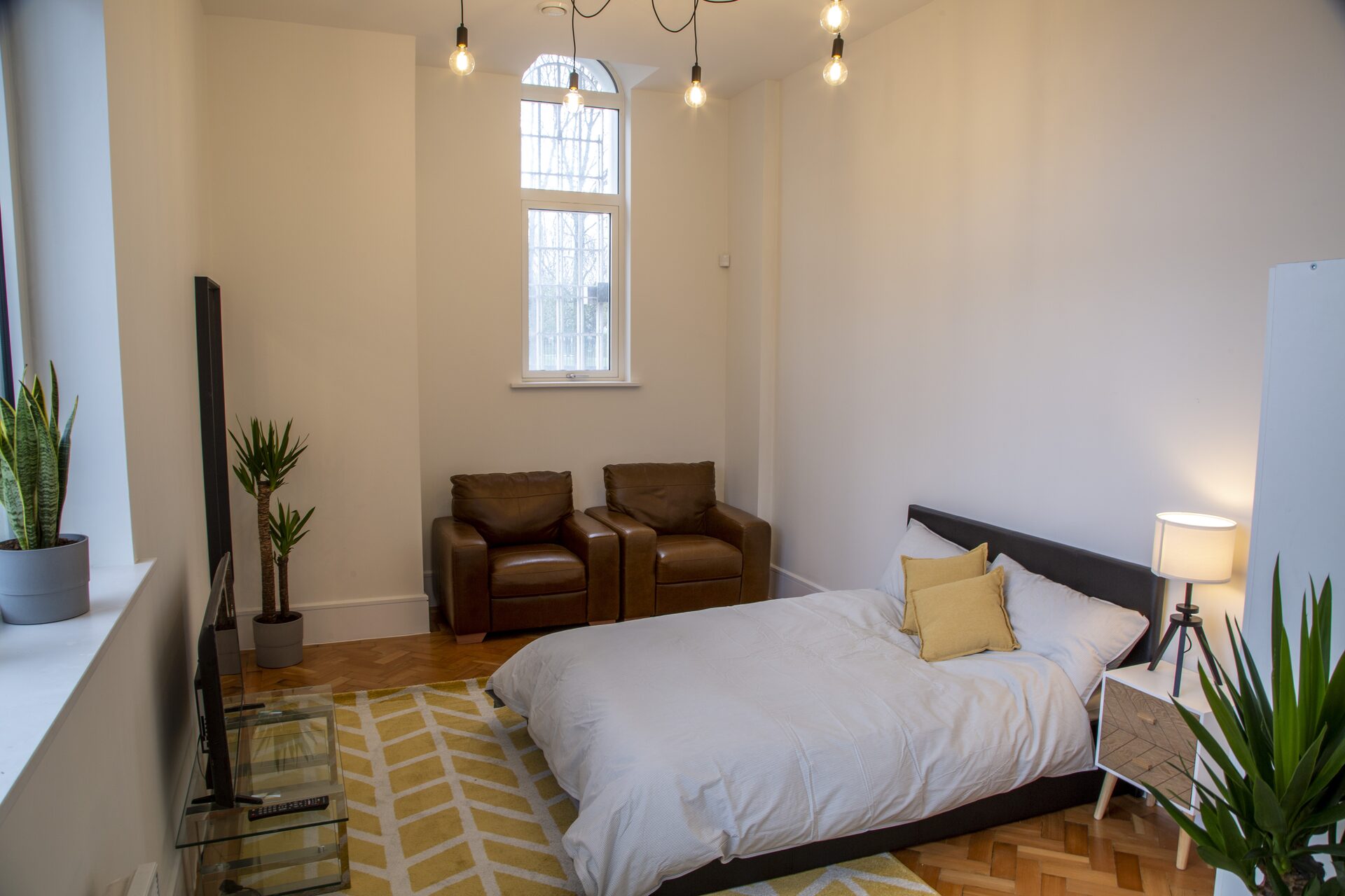Spacious bedroom with high ceilings and leather armchairs